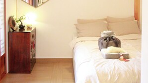Un dormitorio con techo de madera, una cama con ropa de cama blanca, una mesita de noche con lámpara y un espejo en la pared.