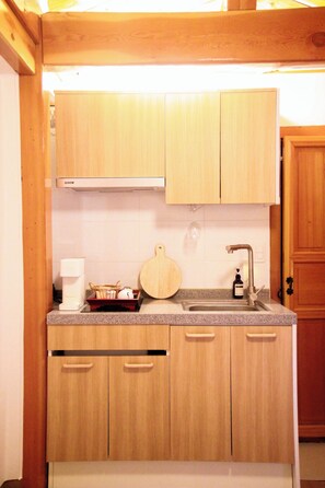 A kitchen with wooden cabinets, a sink, and a countertop. - Travel Light Hanok (Seoul)