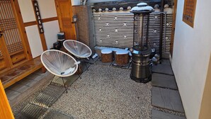 Un patio japonés tradicional con esteras de tatami, una puerta de madera y un farol de piedra.