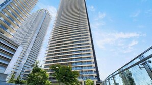 A high-rise building with a modern design, featuring multiple balconies and a clear sky in the background.