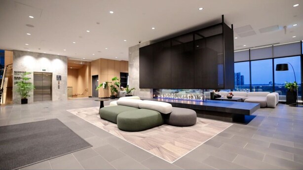 A modern lobby with a fireplace, seating area, and a view of the city.