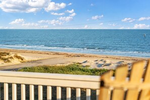 A beach view with a clear sky, a sandy shore, and a wooden fence in the foreground. - Crystal Beach 4BR Home | Pickleball Court | Ocean Views (Crystal Beach)