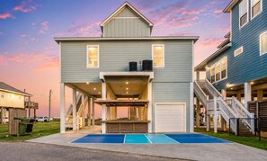 A two-story house with a covered patio, a garage, and a pool. - Crystal Beach 4BR Home | Pickleball Court | Ocean Views (Crystal Beach)