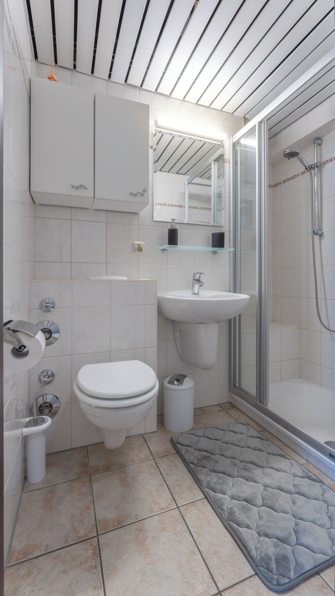 Une salle de bain moderne équipée de toilettes, d’un lavabo et d’une douche.