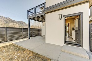 Ein modernes Haus mit überdachter Terrasse, einer Garagentür und Blick auf die Berge.