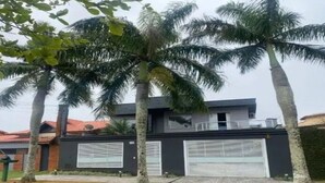 Ein modernes, zweistöckiges Haus mit Garage, umgeben von Palmen.