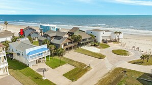 An aerial view of a coastal residential area with houses, a beach, and a clear sky. - Great Views from Rooftop Deck, 4th House from Beach, Chill Vibes! (Galveston)