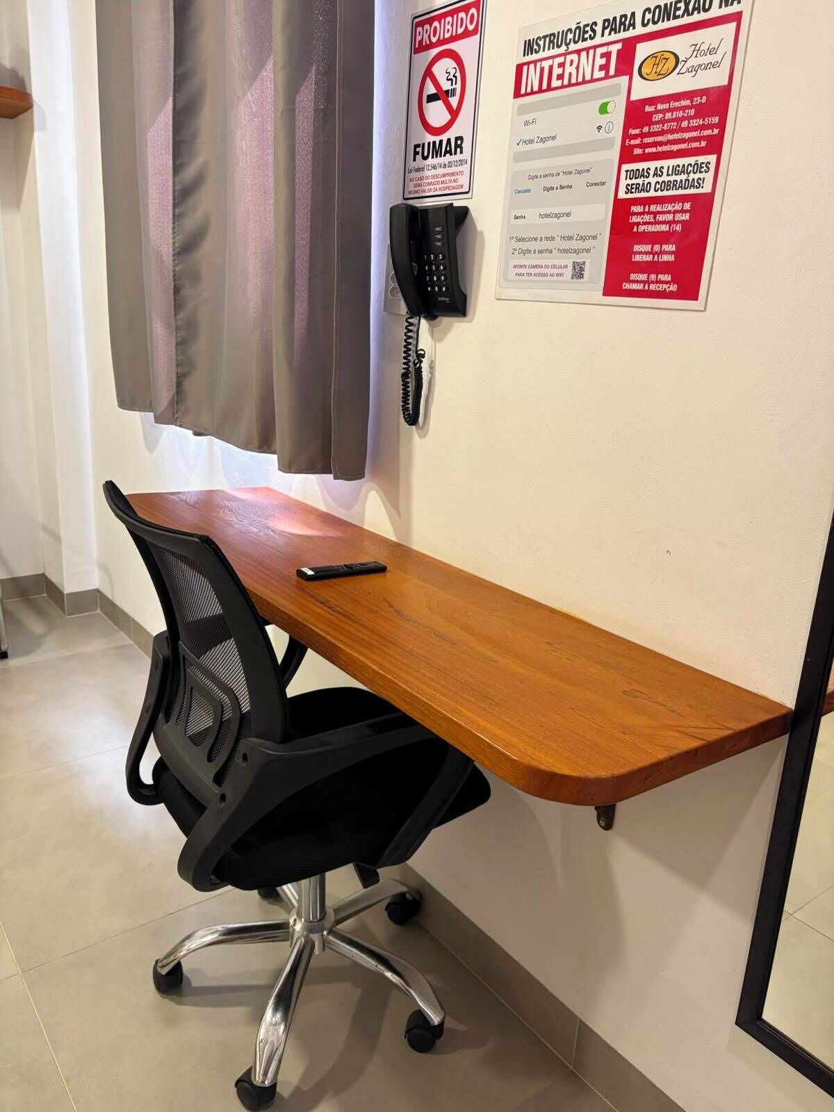 Uma mesa com telefone, uma cadeira e um aviso proibindo fumar.