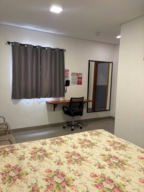 A hotel room with a bed, a desk, a chair, a telephone, and a window with curtains. - HOTEL ZAGONEL  (Chapecó)