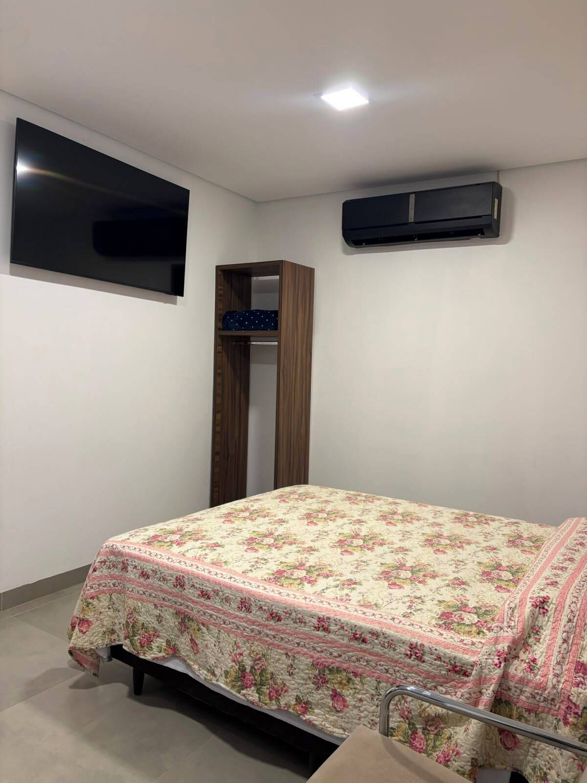 Un dormitorio con cama, armario, televisión de pantalla plana y aire acondicionado.
