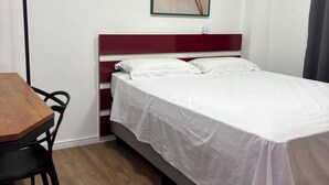 Habitació d'hotel amb llit, escriptori i quadre penjat a la paret.