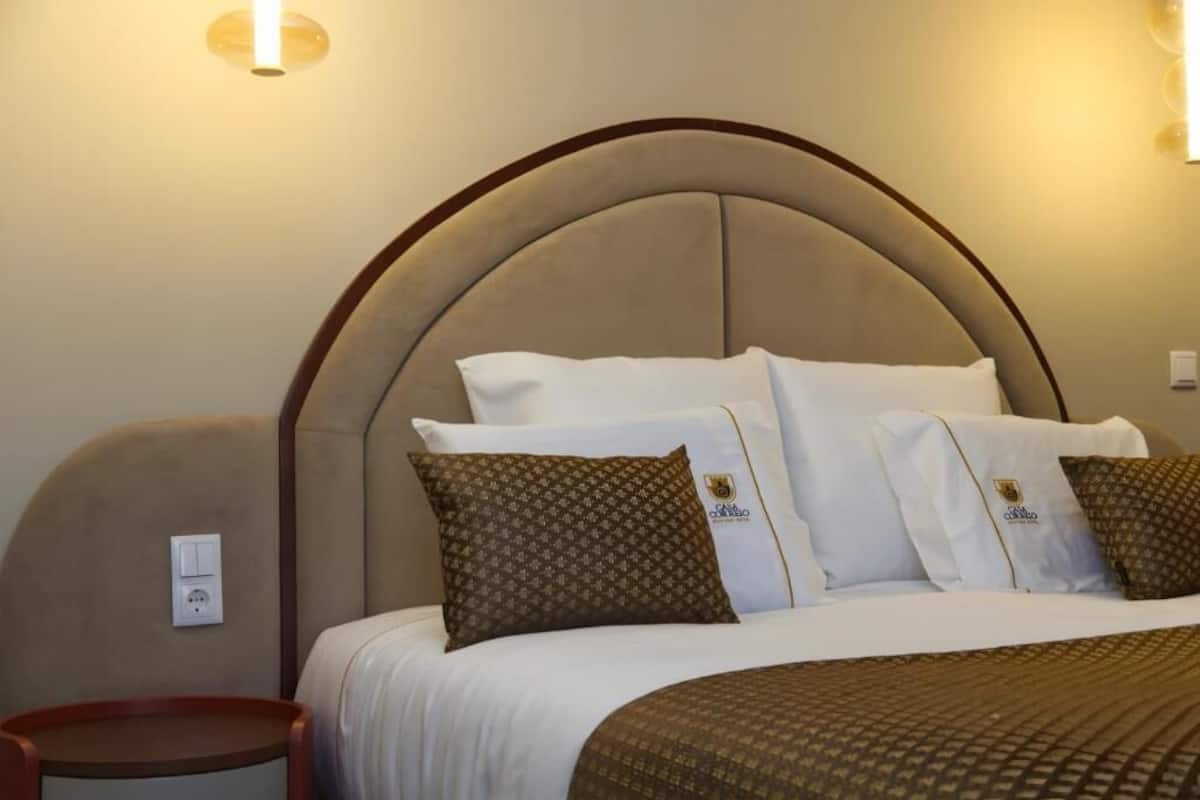 A hotel room with a large bed, a round headboard, and a bedside table.