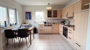 A modern kitchen with wooden cabinets, a dining area with a table and chairs, and a view through the window. - Large, cozy vacation apartment in the heart of the Kraichgau. (Kraichtal)