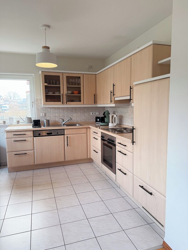 A modern kitchen with light wood cabinets, a stainless steel sink, and a built-in oven. - Large, cozy vacation apartment in the heart of the Kraichgau. (Kraichtal)