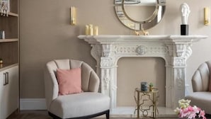A living room with a fireplace, a round mirror, and a modern chandelier.
