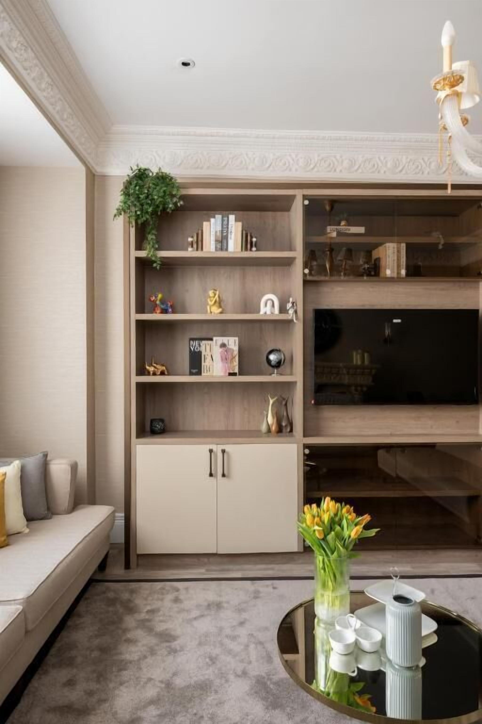 Un salon moderne avec une bibliothèque intégrée en bois, une table basse ronde agrémentée d’objets décoratifs et un canapé.