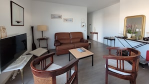 A living room with a brown leather sofa, wooden chairs, a TV, a chandelier, and framed pictures on the wall. - Superb T4 80m2 - Terrace 40m2 - 4/6pers - fully equipped and linen included (Vannes)