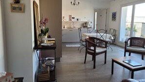 A modern kitchen with a dining area, featuring a chandelier, wooden furniture, and a view through the window. - Superb T4 80m2 - Terrace 40m2 - 4/6pers - fully equipped and linen included (Vannes)