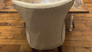 Una mesa de comedor con seis sillas, suelo de madera y un mueble de madera oscura al fondo.