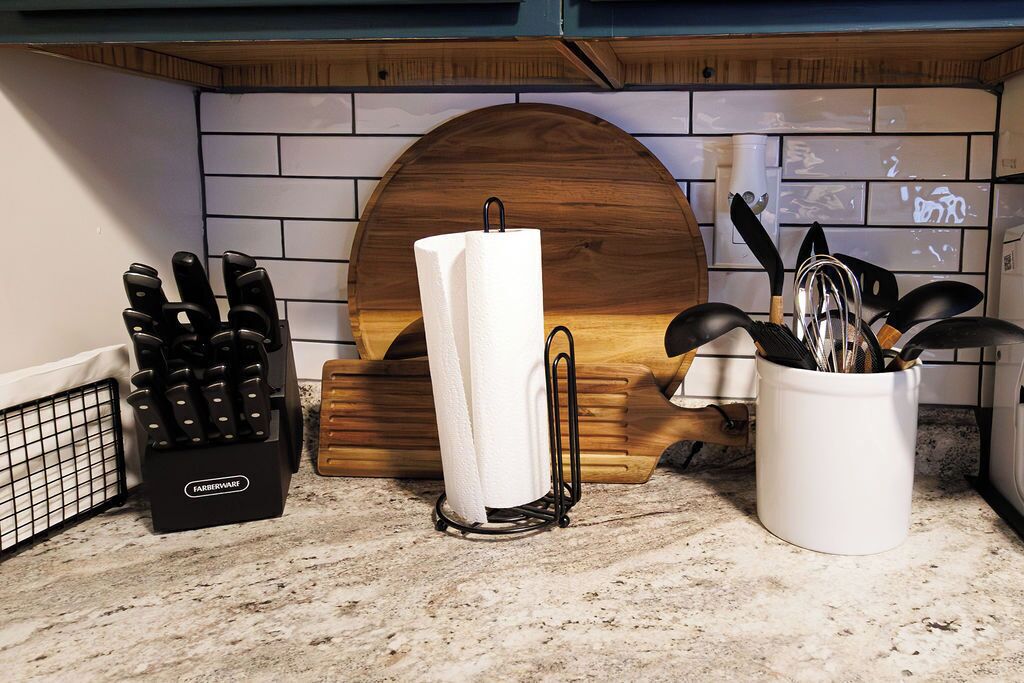 A kitchen counter with a knife block, a paper towel holder, and a utensil holder.
