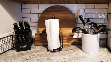 A kitchen counter with a knife block, a paper towel holder, and a utensil holder.