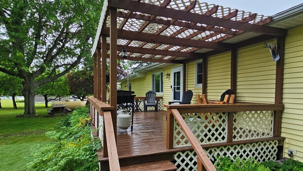 Une terrasse en bois avec une pergola, une table de pique-nique et des chaises.