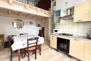Eine kompakte Küche mit Mikrowelle, Herd und Backofen, Holzschränken und einem Essbereich mit Tisch und Stühlen.