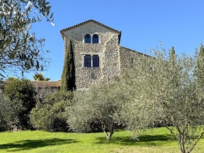 A stone building with a tower, surrounded by greenery and a clear sky. - Mas Grange Neuve (Potelières)