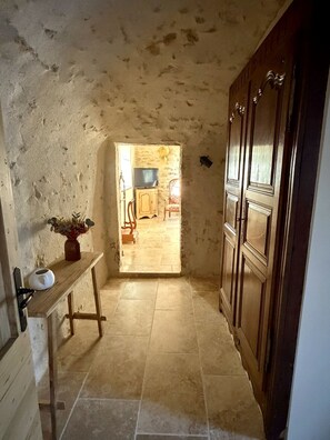 A narrow hallway with a wooden cabinet on the right and a small table with a vase on the left. - Mas Grange Neuve (Potelières)