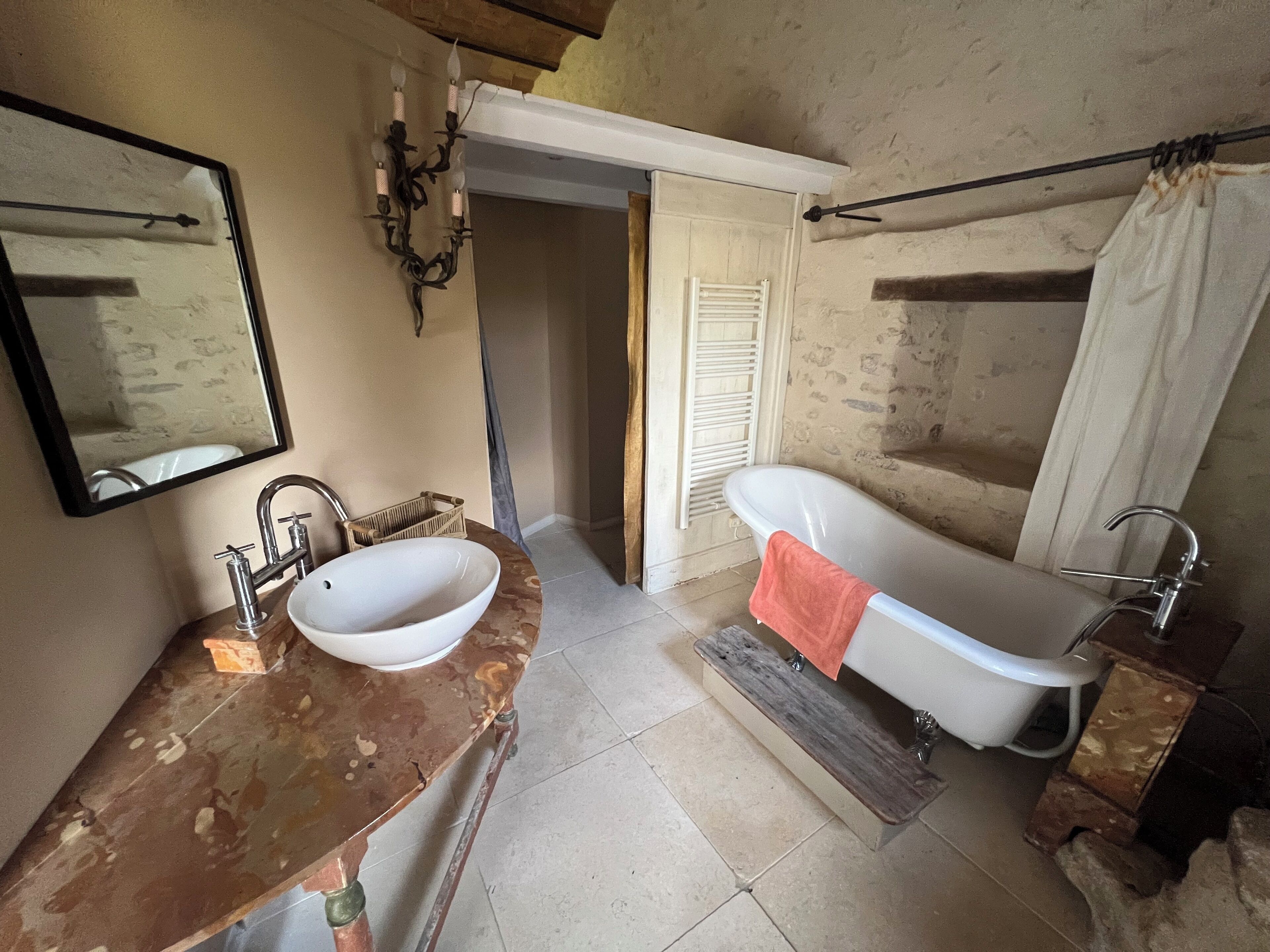 A bathroom with a white sink, a freestanding bathtub, and a mirror.
