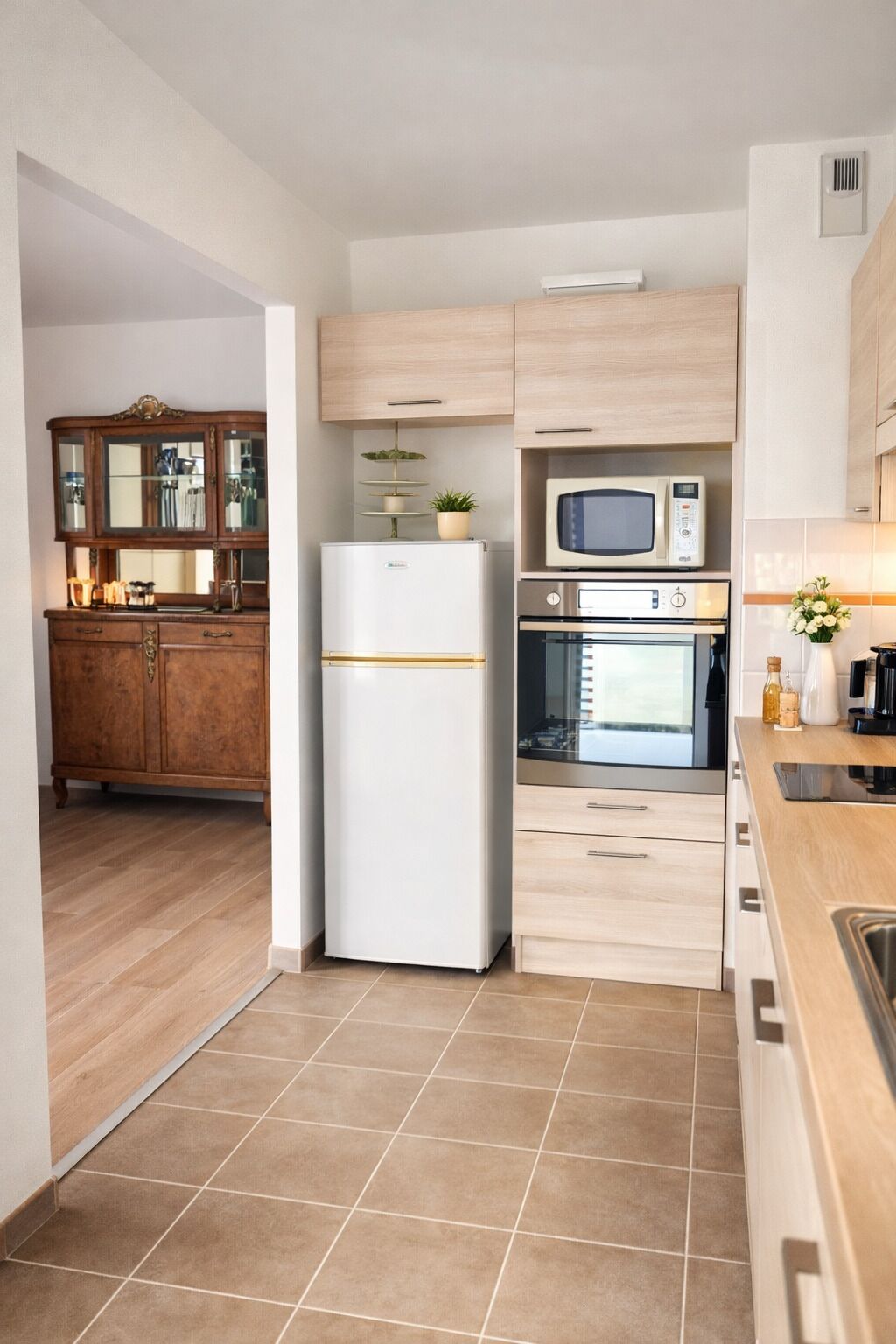 A modern kitchen with a refrigerator, microwave, oven, and wooden cabinets.