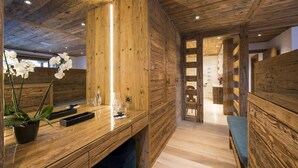 Un interior de madera con una recepción, una orquídea en maceta y un banco de madera.