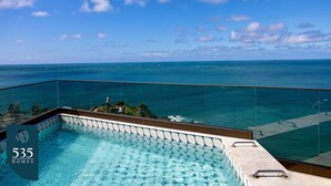 Ein Pool mit Glasgeländer und Blick auf den Ozean.