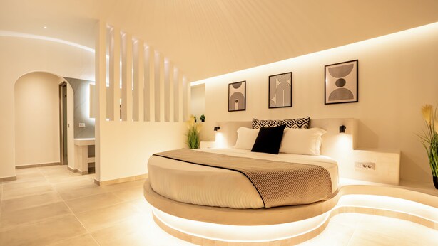 Un dormitorio moderno con una cama curva, un televisor montado en la pared y una escalera.