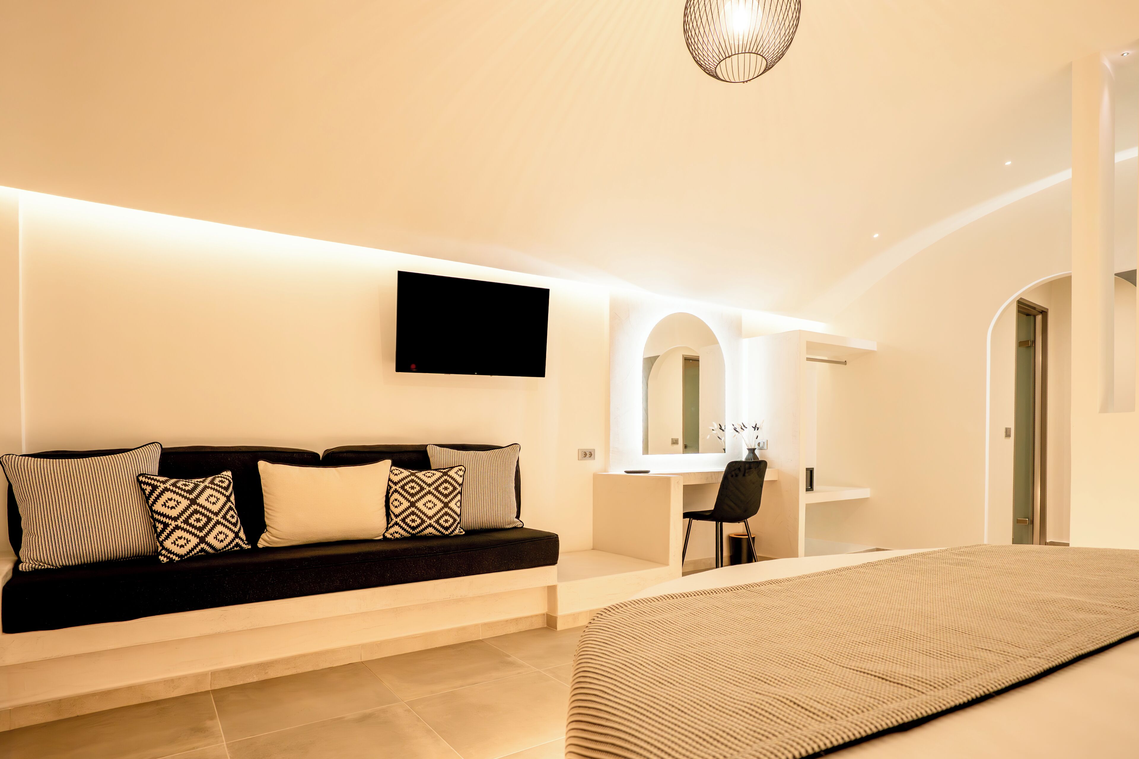 A modern living room with a sofa, a flat-screen TV, a desk, and a chair.