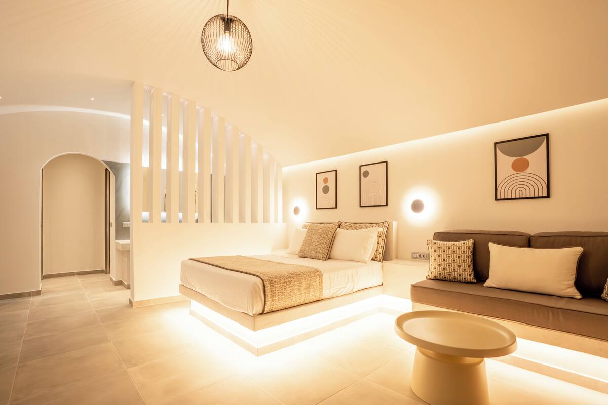 Une chambre à coucher moderne, avec un lit, un canapé, une table basse et un luminaire fixé au mur.