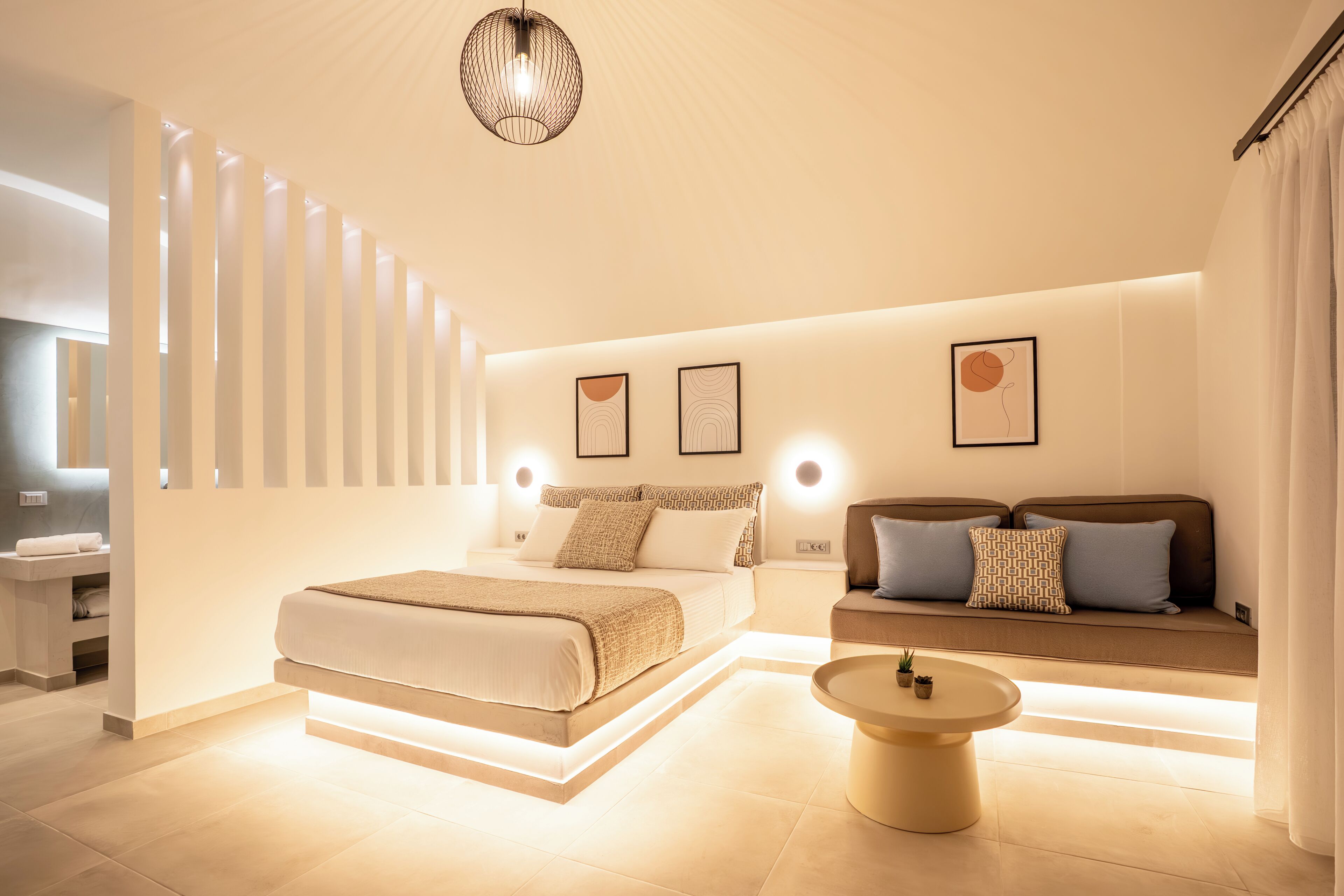 Ein modernes Schlafzimmer mit Bett, Sofa, Nachttischen und Wandleuchten.