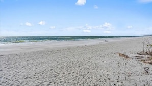 Une plage avec une vaste étendue de sable et l’océan en toile de fond.