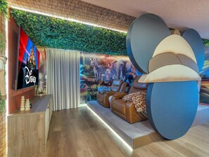 Una sala de estar moderna con televisor de pantalla plana, asientos cómodos, un mural y una pared verde.