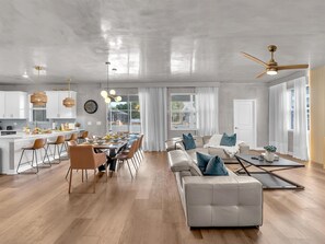 Ein großzügiger Wohnbereich mit Esstisch, Sofas und Deckenventilator.
