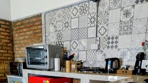A kitchen with a microwave, toaster, red refrigerator, and patterned backsplash. - Warm and modern apartment (Esquel)