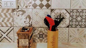 A kitchen with patterned tiles, a wooden spice rack, and a sign that reads "LA VIDA ES UN REGALO". - Warm and modern apartment (Esquel)