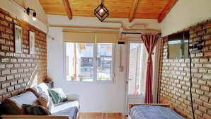 A cozy room with a wooden ceiling, a brick wall, a large window, and a bed with a wooden headboard. - Warm and modern apartment (Esquel)
