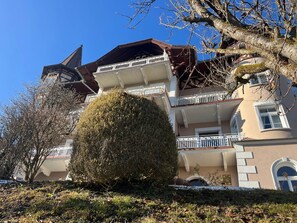 Ein mehrstöckiges Gebäude mit Balkonen, einem großen Baum in der Mitte und Schnee auf dem Boden.