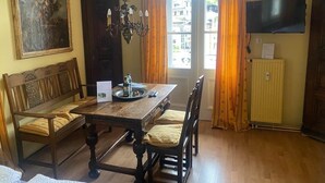 A dining area with a wooden table, chairs, a chandelier, and a painting on the wall. - Vacation apartment Alpenglühen - Untersberg view (Berchtesgaden)