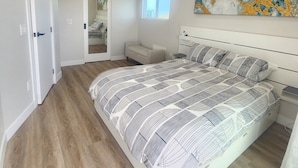 Una camera da letto con un letto grande, una ventola a soffitto, una finestra e una porta.