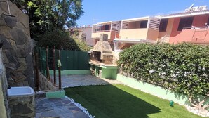 A well-maintained outdoor area with artificial grass, a stone wall, and a stone sink. - Villa with garden in Villasimius (Cagliari)