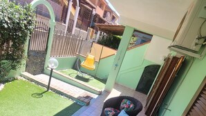 A covered patio area with wicker furniture and a small lawn. - Villa with garden in Villasimius (Cagliari)