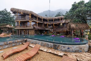 A resort with a pool, wooden deck, and thatched-roof buildings. - Puluong Qui E Ora (Ba Thuoc)