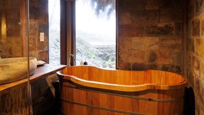 Een houten badkuip in een betegelde badkamer met uitzicht op een waterval.